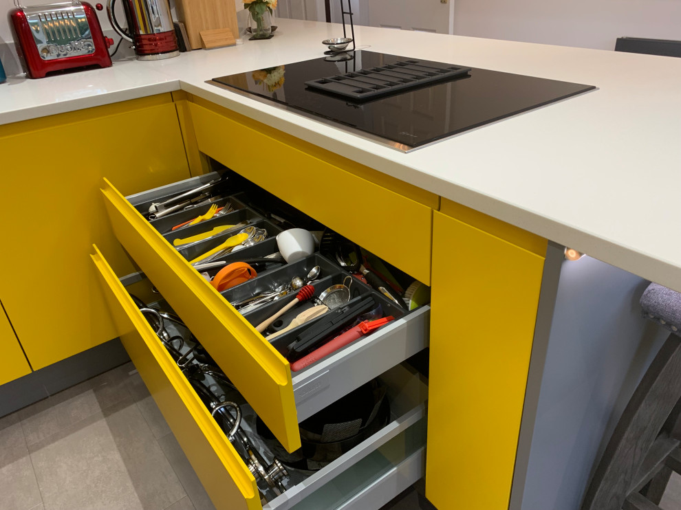 This is an example of a mid-sized contemporary u-shaped separate kitchen in Buckinghamshire with flat-panel cabinets, yellow cabinets, quartzite benchtops, white splashback, panelled appliances, vinyl floors, a peninsula, grey floor and white benchtop.