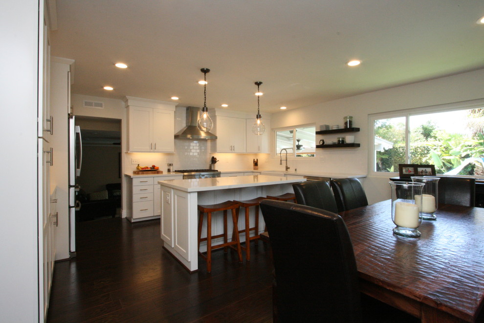 Eat-in kitchen - large transitional u-shaped dark wood floor eat-in kitchen idea in Orange County with a farmhouse sink, shaker cabinets, white cabinets, quartz countertops, white backsplash, ceramic backsplash, stainless steel appliances and an island
