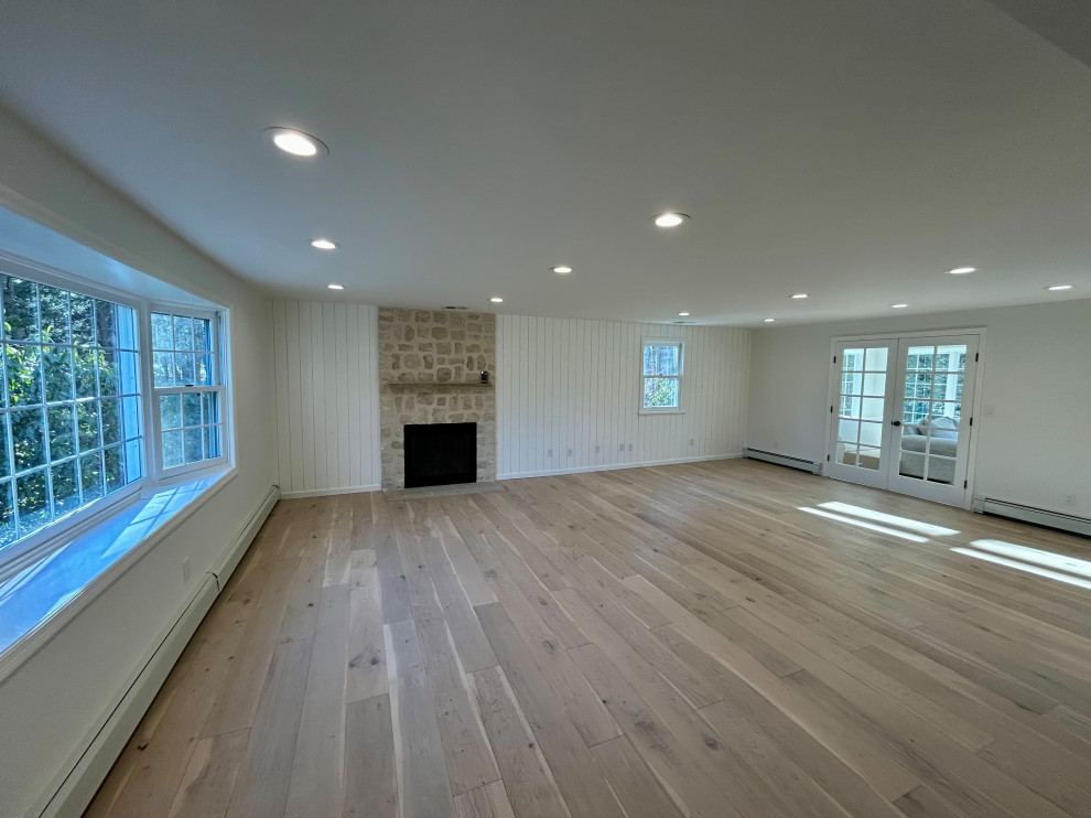 Foto på ett stort funkis separat vardagsrum, med ett finrum, vita väggar, ljust trägolv, en standard öppen spis, en spiselkrans i tegelsten och flerfärgat golv