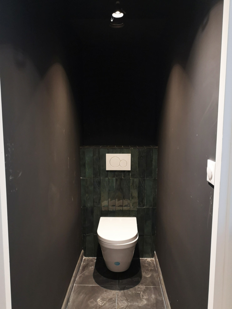 Immagine di un piccolo bagno di servizio design con WC sospeso, piastrelle verdi, piastrelle in ceramica, pareti nere, pavimento con piastrelle in ceramica e pavimento nero