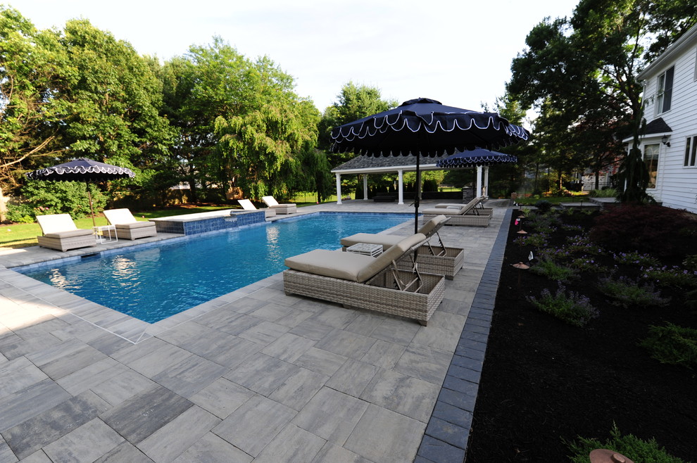 Large traditional backyard rectangular lap pool in Philadelphia with a hot tub and natural stone pavers.