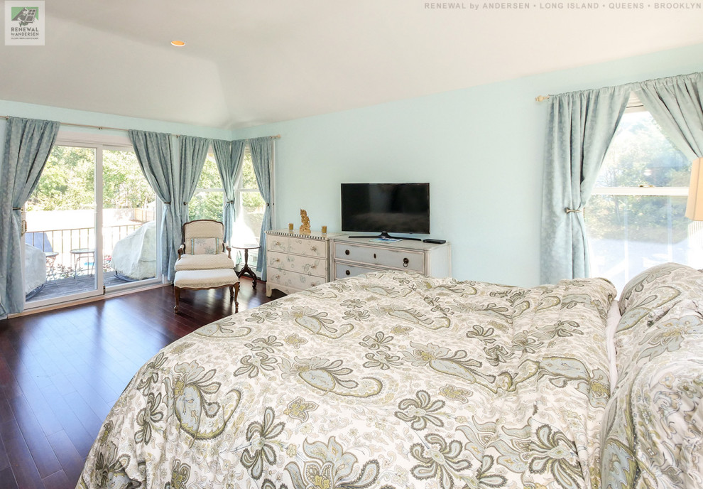 Großes Hauptschlafzimmer ohne Kamin mit blauer Wandfarbe, Laminat, braunem Boden und gewölbter Decke in New York