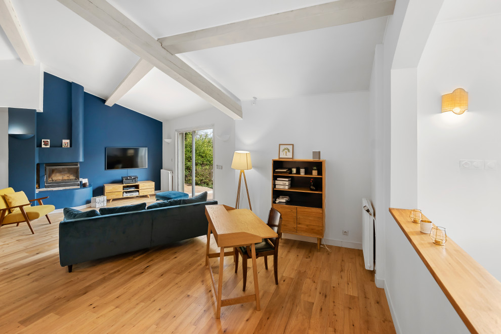 Inspiration pour un grand salon ouvert avec un mur bleu, parquet clair, un poêle à bois, un téléviseur fixé au mur, un sol beige, poutres apparentes et un plafond cathédrale.