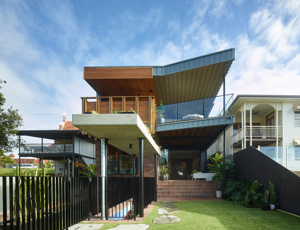 This is an example of a contemporary two-storey grey house exterior in Brisbane with mixed siding and a flat roof.