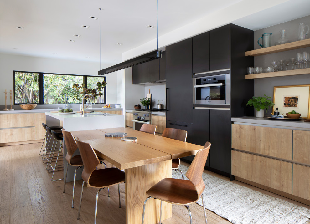 Example of a mid-sized danish galley light wood floor and brown floor eat-in kitchen design in San Francisco with a single-bowl sink, flat-panel cabinets, brown cabinets, quartzite countertops, gray backsplash, quartz backsplash, paneled appliances, an island and gray countertops