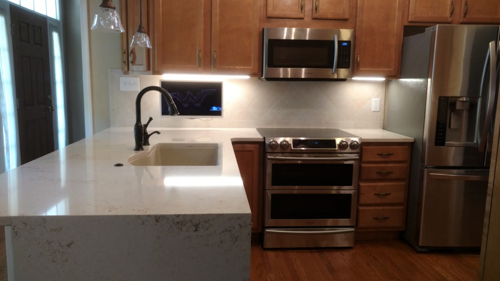 Example of a small transitional l-shaped light wood floor and multicolored floor kitchen design with an undermount sink, recessed-panel cabinets, medium tone wood cabinets, laminate countertops, multicolored backsplash, ceramic backsplash, stainless steel appliances, no island and multicolored countertops