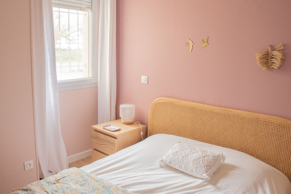 Diseño de dormitorio moderno de tamaño medio con paredes rosas y suelo laminado