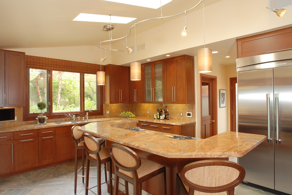 This is an example of a transitional kitchen in Los Angeles with a double-bowl sink, shaker cabinets, medium wood cabinets, granite benchtops, stainless steel appliances, orange splashback, stone slab splashback, slate floors and multi-coloured floor.