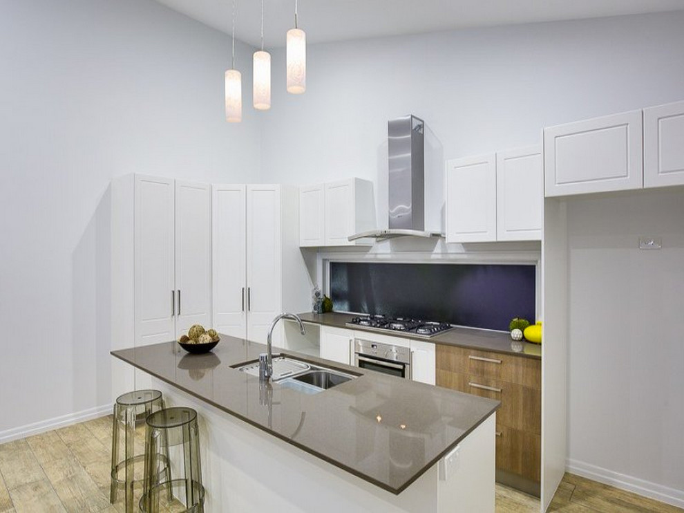 Small contemporary single-wall open plan kitchen in Brisbane with a double-bowl sink, shaker cabinets, white cabinets, granite benchtops, window splashback, stainless steel appliances, light hardwood floors and with island.