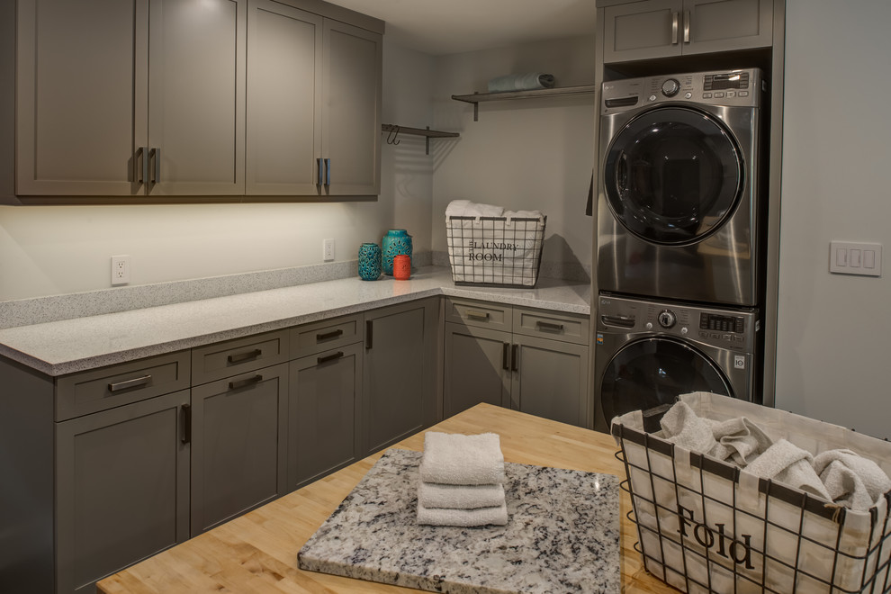 This is an example of a large contemporary dedicated laundry room in San Francisco with an undermount sink, shaker cabinets, grey cabinets, quartz benchtops, white walls, porcelain floors and a stacked washer and dryer.