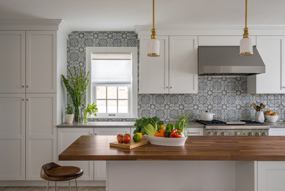 Inspiration for a contemporary u-shaped separate kitchen in Boston with a farmhouse sink, shaker cabinets, white cabinets, stainless steel appliances, with island, grey floor, wood benchtops, multi-coloured splashback and ceramic splashback.