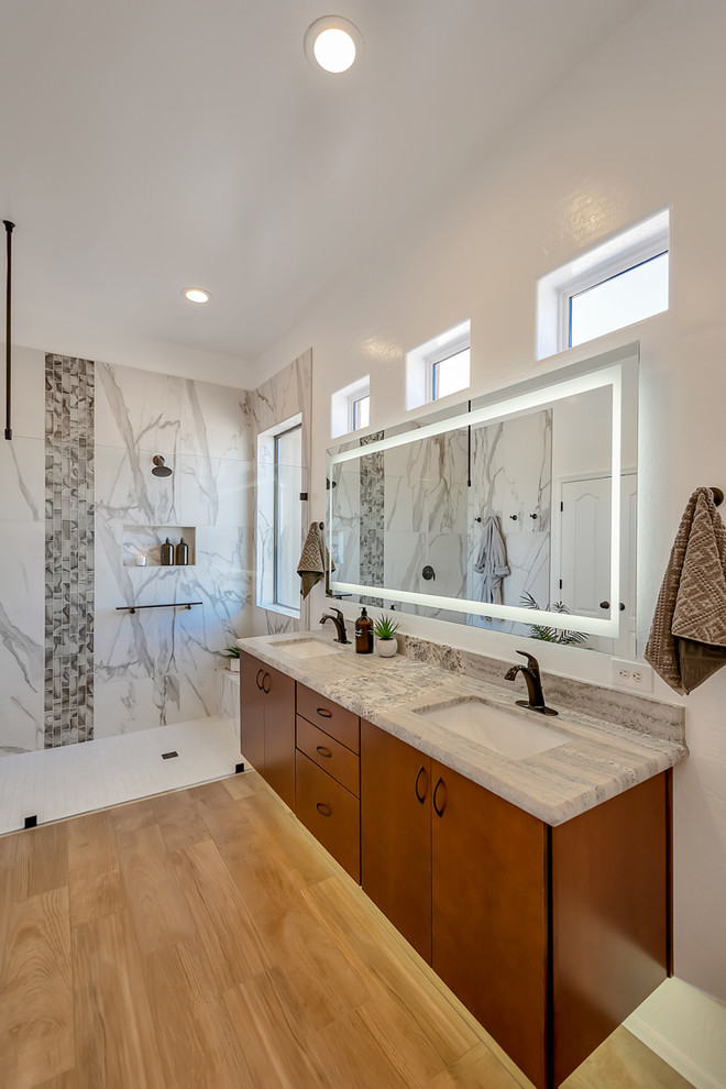 Photo of a mid-sized contemporary master bathroom in Phoenix with flat-panel cabinets, medium wood cabinets, a curbless shower, a two-piece toilet, white tile, porcelain tile, white walls, porcelain floors, an undermount sink, granite benchtops, brown floor, an open shower and grey benchtops.