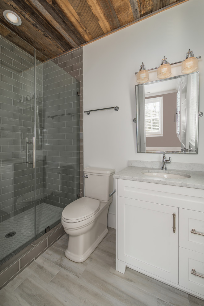 Photo of a mid-sized modern 3/4 bathroom in Charleston with shaker cabinets, white cabinets, an alcove shower, a two-piece toilet, gray tile, ceramic tile, white walls, porcelain floors, an undermount sink, quartzite benchtops, multi-coloured floor, a hinged shower door and white benchtops.