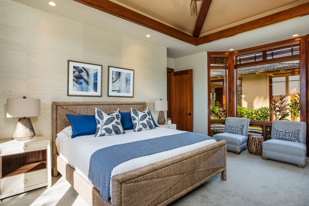 This is an example of a tropical guest bedroom in Hawaii with beige walls, carpet and grey floor.