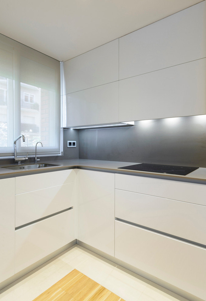 Photo of a mid-sized contemporary l-shaped eat-in kitchen in Other with flat-panel cabinets, white cabinets, grey splashback and no island.