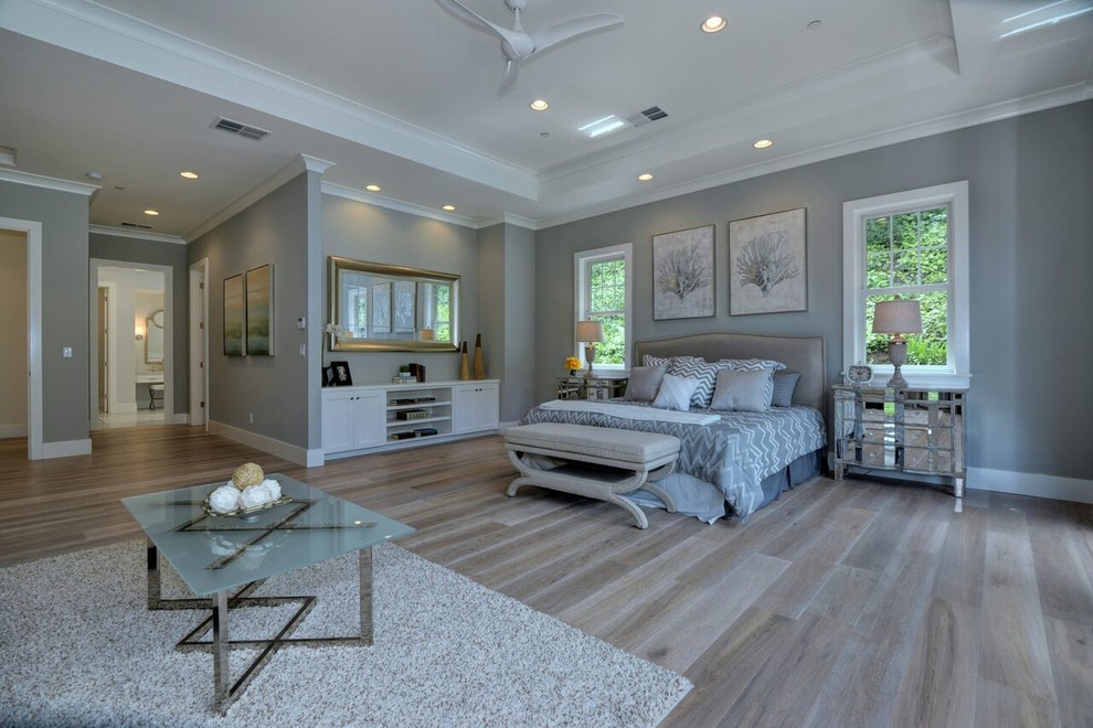 This is an example of a large transitional master bedroom in San Francisco with grey walls, light hardwood floors, no fireplace and brown floor.