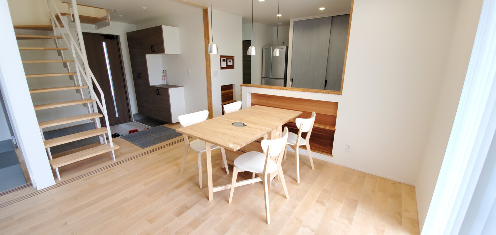Foto på en liten minimalistisk matplats med öppen planlösning, med vita väggar, ljust trägolv och beiget golv