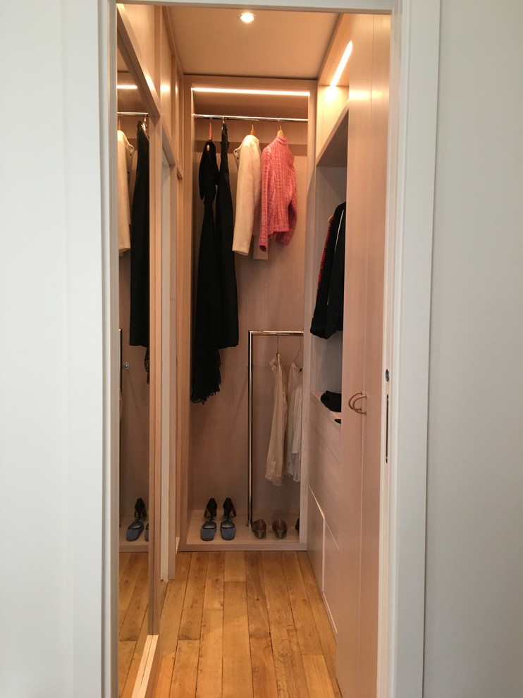 Design ideas for a small transitional gender-neutral dressing room in Paris with light wood cabinets, light hardwood floors and brown floor.