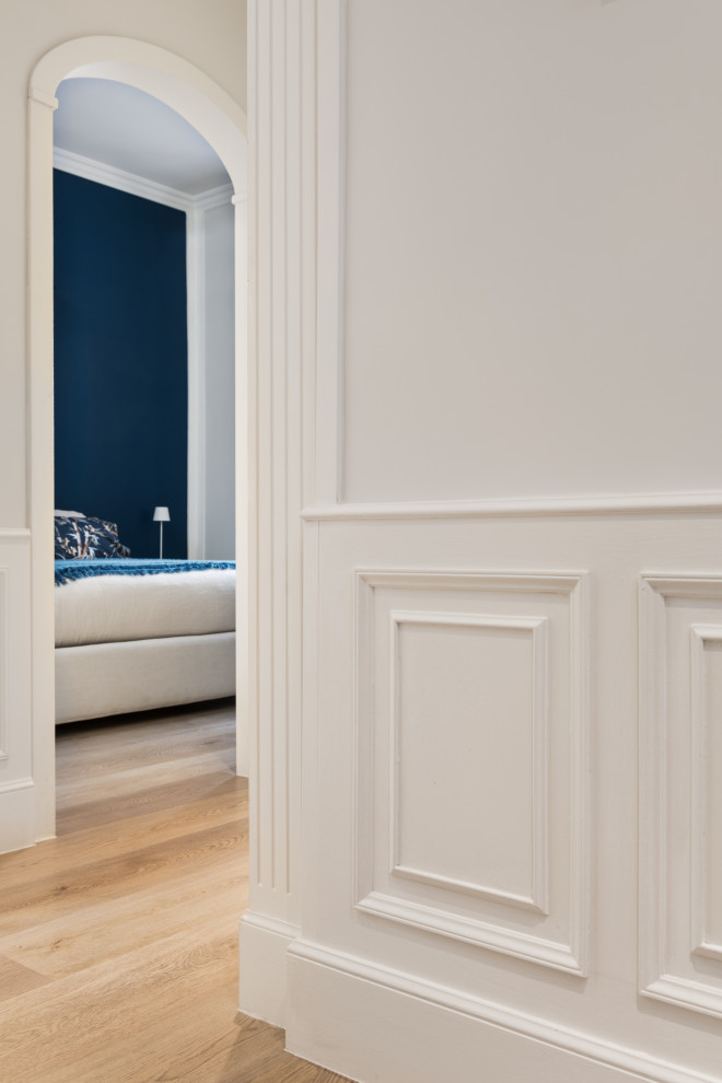 Cette image montre un couloir design avec un mur blanc, parquet clair et boiseries.