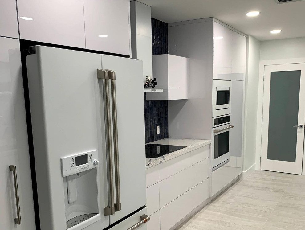 Small modern galley kitchen in Miami with an undermount sink, flat-panel cabinets, white cabinets, quartz benchtops, blue splashback, glass tile splashback, white appliances and white benchtop.