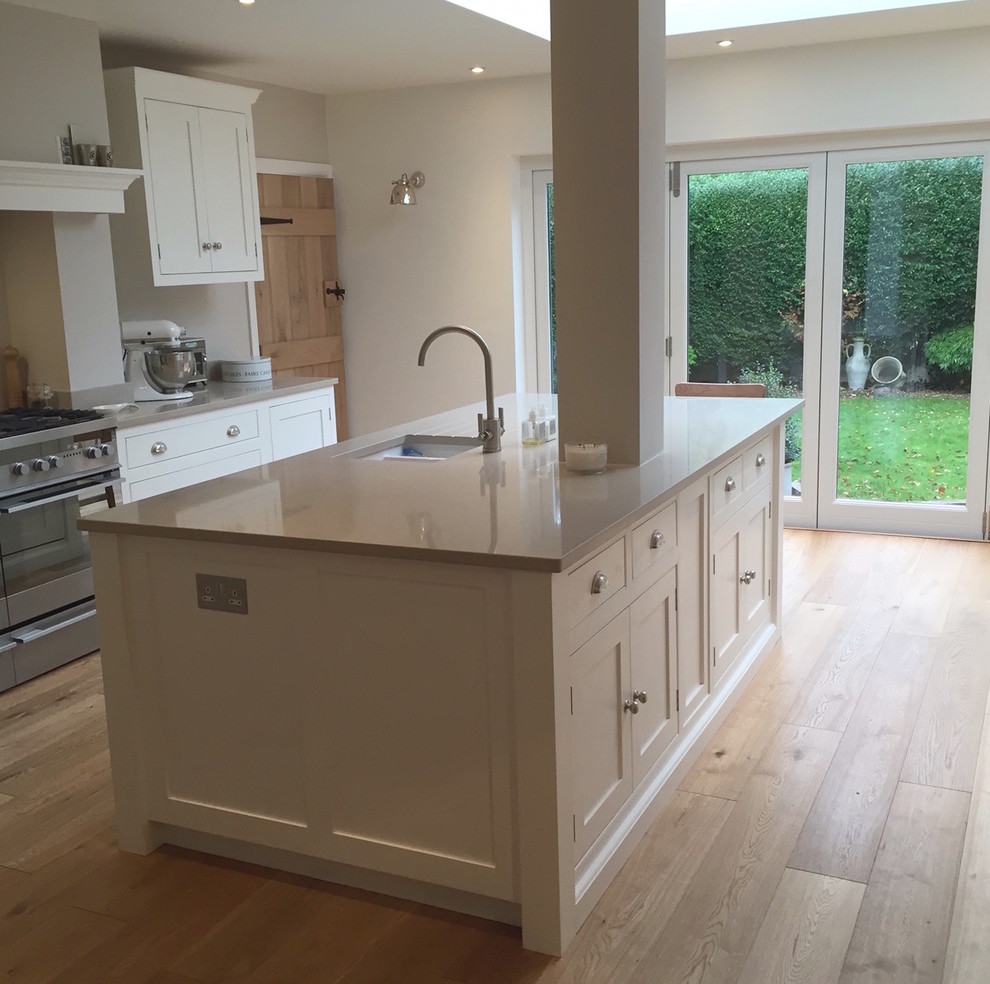 Photo of a large traditional l-shaped eat-in kitchen in Surrey with a drop-in sink, flat-panel cabinets, white cabinets, quartzite benchtops, with island and white benchtop.