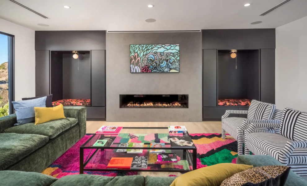 Photo of an expansive contemporary open concept living room in Los Angeles with a library, grey walls, light hardwood floors, a hanging fireplace, a concrete fireplace surround, a built-in media wall, beige floor, vaulted and planked wall panelling.