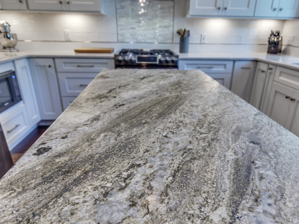 Example of a mid-sized transitional u-shaped brown floor eat-in kitchen design in St Louis with white cabinets, granite countertops, white backsplash, subway tile backsplash, stainless steel appliances, an island and multicolored countertops