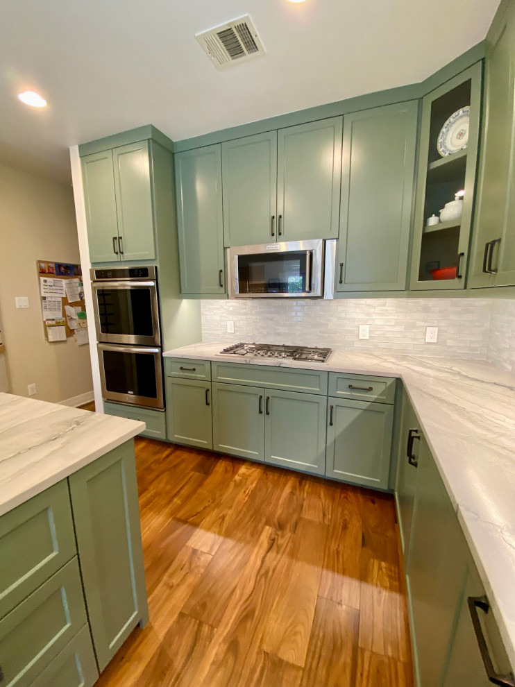 オースティンにある高級な広いミッドセンチュリースタイルのおしゃれなキッチン (エプロンフロントシンク、落し込みパネル扉のキャビネット、緑のキャビネット、珪岩カウンター、白いキッチンパネル、ガラスタイルのキッチンパネル、シルバーの調理設備、無垢フローリング、茶色い床、白いキッチンカウンター、板張り天井) の写真