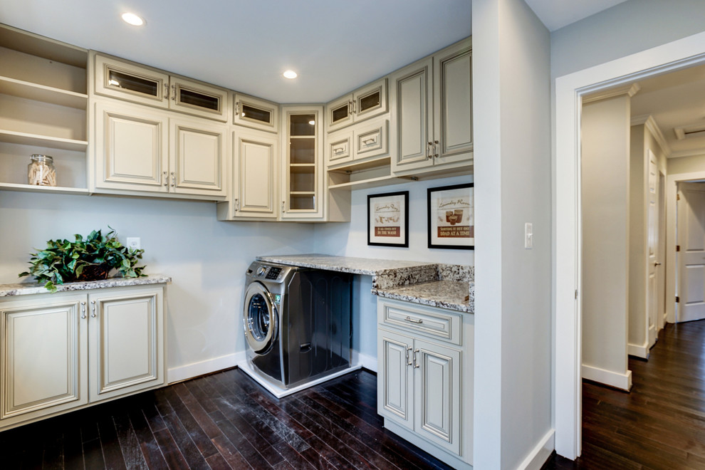 This is an example of a mid-sized traditional l-shaped dedicated laundry room in DC Metro with raised-panel cabinets, white cabinets, granite benchtops, white walls, dark hardwood floors and a side-by-side washer and dryer.