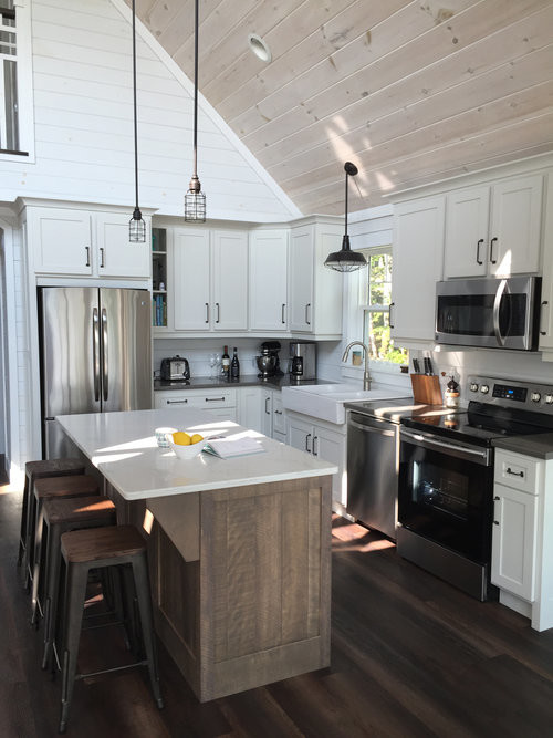 Mid-sized transitional u-shaped dark wood floor and brown floor open concept kitchen photo with a farmhouse sink, shaker cabinets, white cabinets, quartz countertops, white backsplash, stainless steel appliances, an island and white countertops