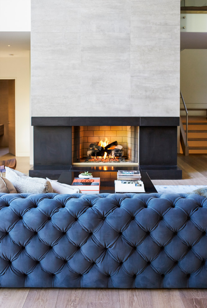 Mid-sized contemporary open concept living room in Vancouver with white walls, light hardwood floors, a standard fireplace, a concrete fireplace surround and a built-in media wall.