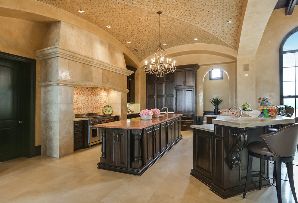 This is an example of an expansive galley eat-in kitchen in Austin with a double-bowl sink, recessed-panel cabinets, dark wood cabinets, quartzite benchtops, multi-coloured splashback, terra-cotta splashback, panelled appliances, travertine floors, multiple islands and beige floor.