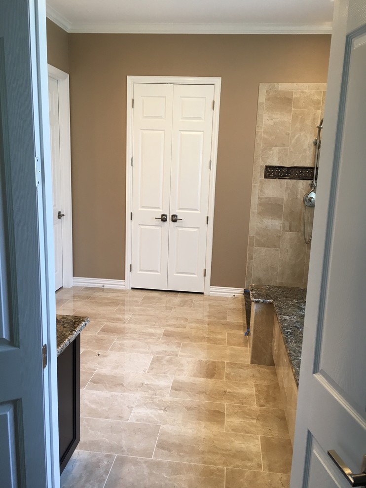 Example of a large transitional master stone tile ceramic tile and beige floor corner shower design in Dallas with dark wood cabinets, an undermount sink, granite countertops, recessed-panel cabinets, brown walls and a hinged shower door