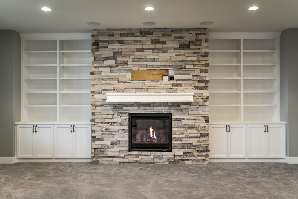 Inspiration for a large country fully buried basement in Omaha with a standard fireplace, a stone fireplace surround, grey walls, carpet and grey floor.