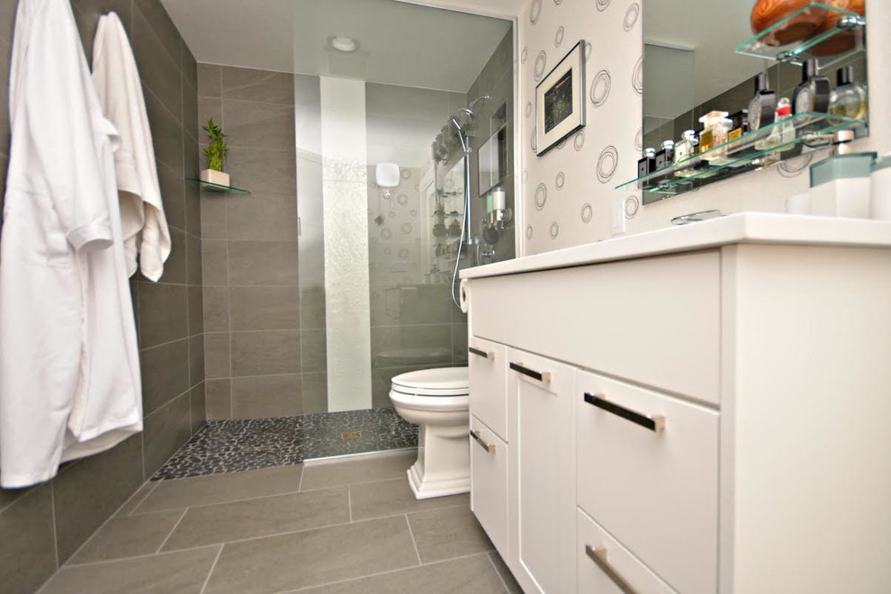 This is an example of a small modern 3/4 bathroom in Boise with flat-panel cabinets, white cabinets, an alcove shower, a two-piece toilet, beige tile, stone tile, beige walls, pebble tile floors, a drop-in sink, solid surface benchtops, beige floor and an open shower.