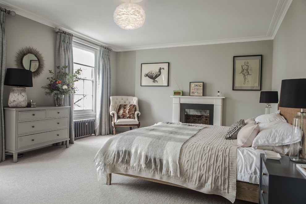 This is an example of a transitional master bedroom in London with grey walls, carpet, a standard fireplace and grey floor.