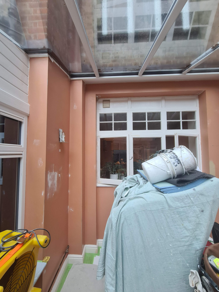 Cette photo montre un porche d'entrée de maison arrière chic de taille moyenne avec une moustiquaire, du carrelage, une extension de toiture et un garde-corps en verre.