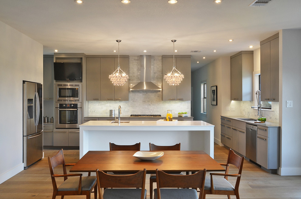 Design ideas for a transitional l-shaped eat-in kitchen in Austin with flat-panel cabinets, grey cabinets, white splashback, stone tile splashback and stainless steel appliances.