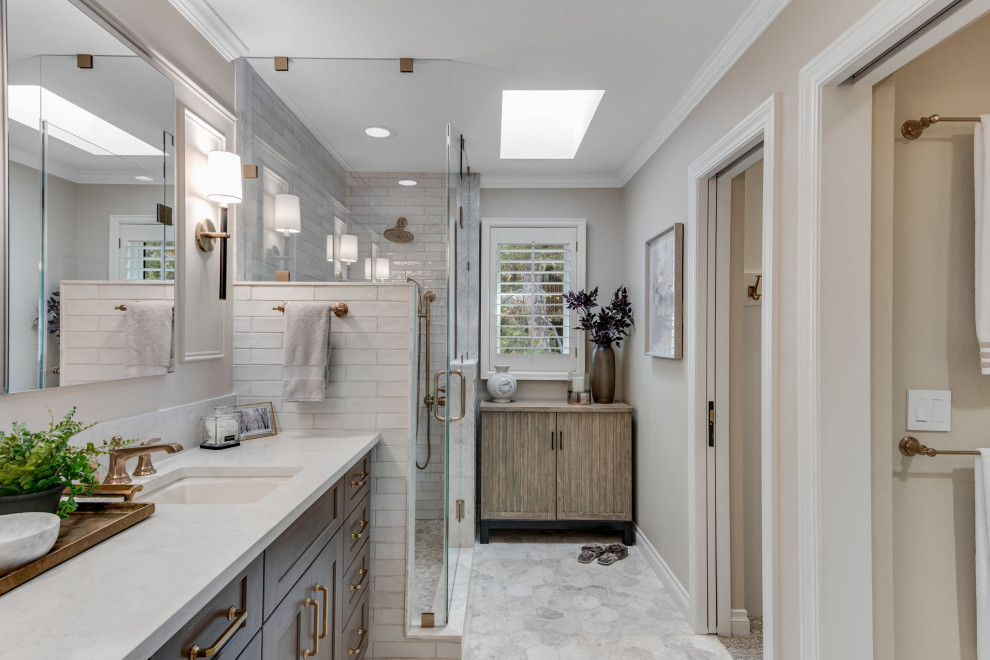 Photo of a mid-sized traditional master bathroom in Denver with recessed-panel cabinets, brown cabinets, an alcove shower, a one-piece toilet, white tile, subway tile, beige walls, marble floors, an undermount sink, engineered quartz benchtops, white floor, a hinged shower door, white benchtops, a niche, a double vanity, a built-in vanity and panelled walls.