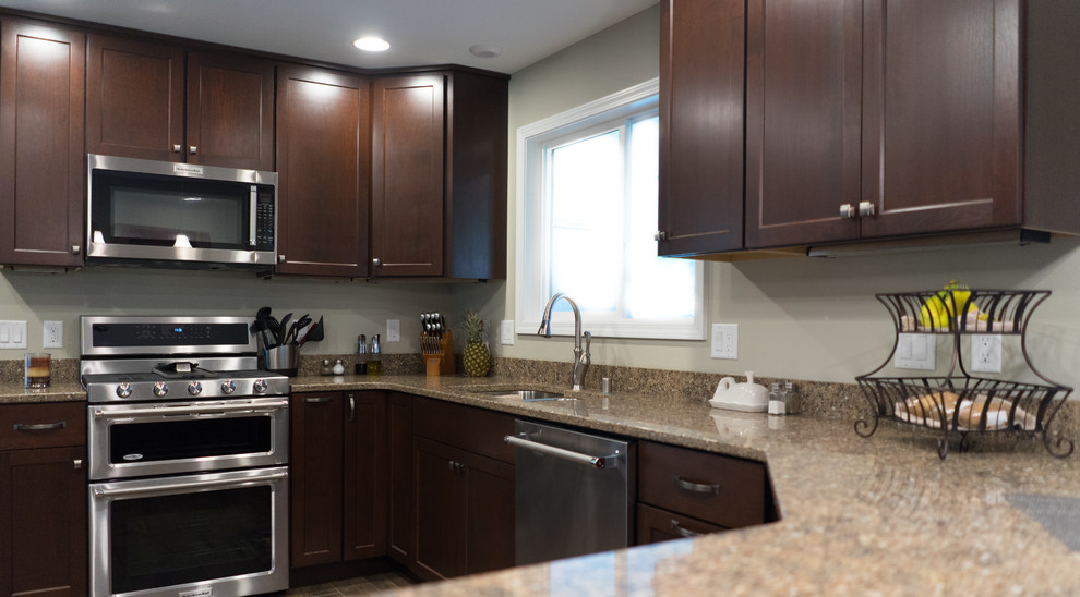 Inspiration for a mid-sized u-shaped ceramic tile enclosed kitchen remodel with an undermount sink, shaker cabinets, dark wood cabinets, quartz countertops, brown backsplash, stainless steel appliances and a peninsula