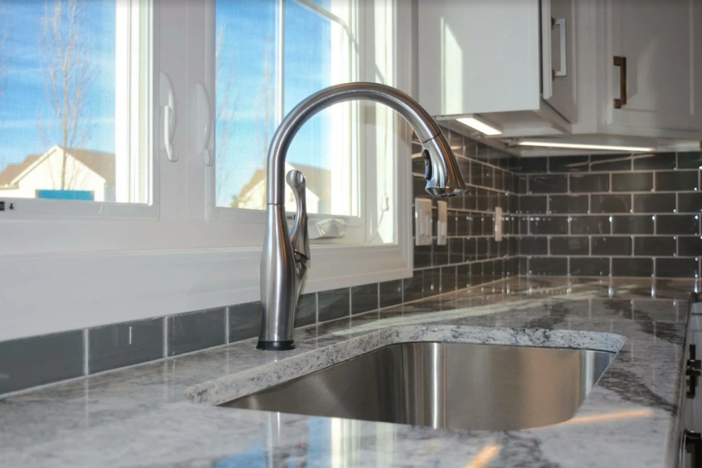 Inspiration for a large transitional l-shaped dark wood floor open concept kitchen remodel with an undermount sink, shaker cabinets, white cabinets, granite countertops, gray backsplash, porcelain backsplash, stainless steel appliances and an island