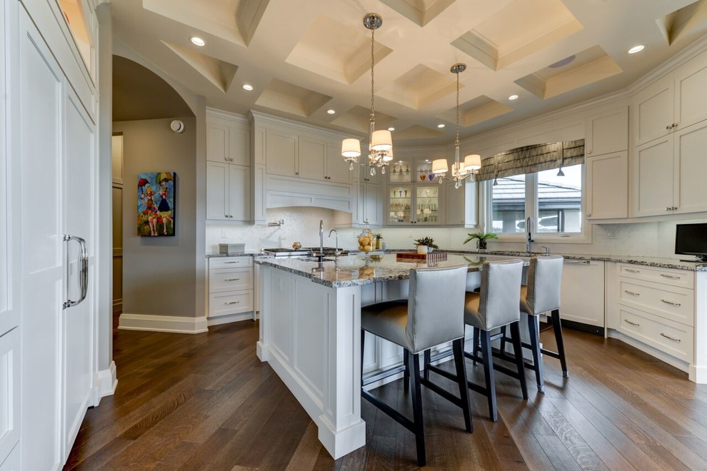 Kitchen - large transitional u-shaped medium tone wood floor and brown floor kitchen idea in Edmonton with shaker cabinets, white cabinets, granite countertops, white backsplash, an island, an undermount sink, glass tile backsplash and paneled appliances