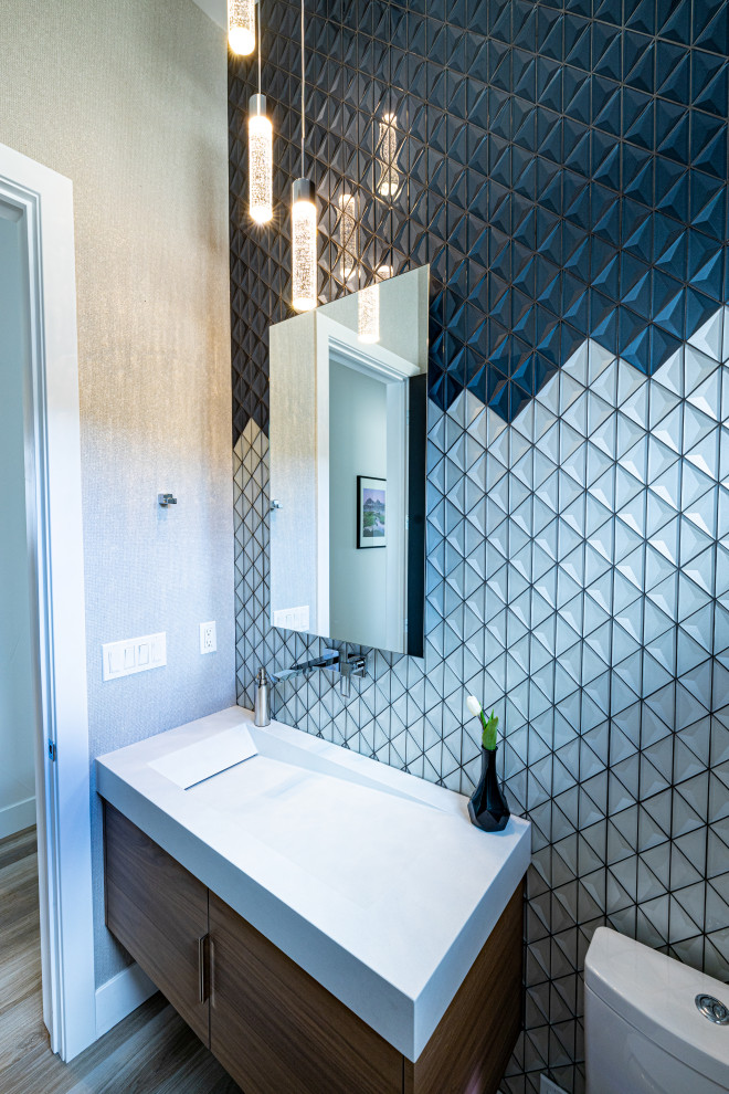This is an example of a small modern powder room with flat-panel cabinets, medium wood cabinets, a bidet, white tile, glass tile, porcelain floors, a trough sink, concrete benchtops, brown floor, white benchtops, a floating vanity and wallpaper.
