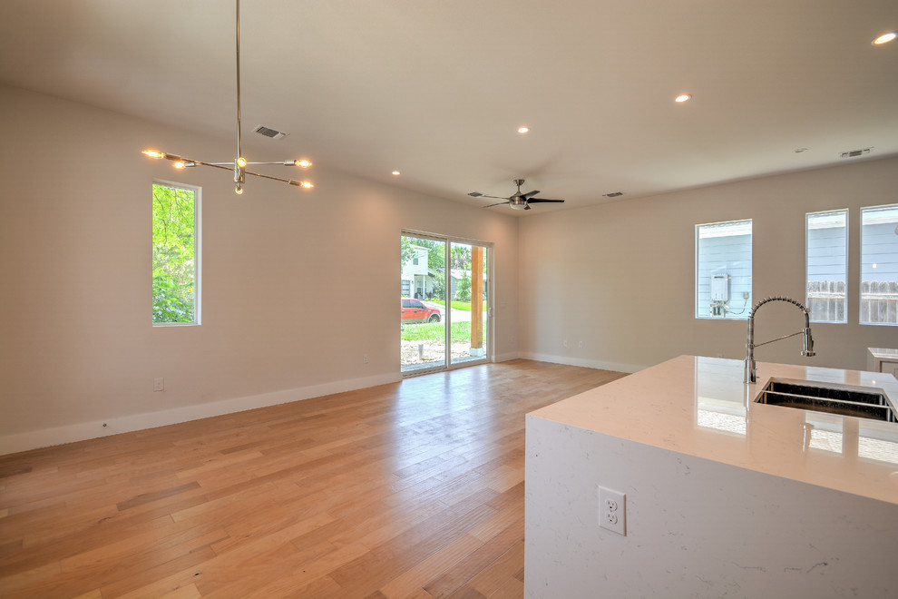 Inspiration for a mid-sized transitional single-wall medium tone wood floor and brown floor open concept kitchen remodel in Austin with a double-bowl sink, shaker cabinets, white cabinets, marble countertops, gray backsplash, stone tile backsplash, stainless steel appliances, an island and white countertops