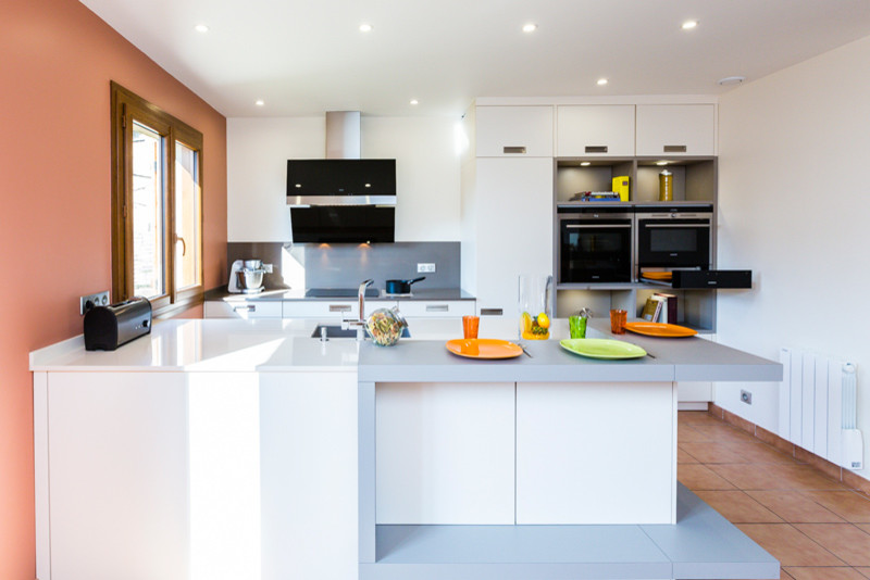 Large contemporary galley eat-in kitchen in Paris with an undermount sink, flat-panel cabinets, beige cabinets, quartzite benchtops, grey splashback, stainless steel appliances, ceramic floors, with island and beige benchtop.