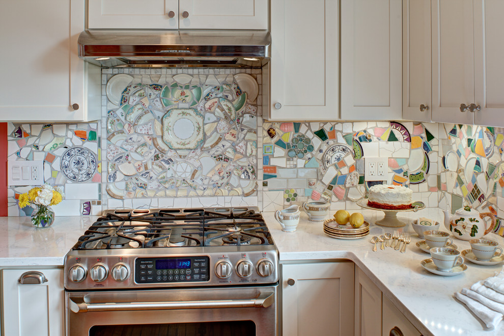 This is an example of a medium sized eclectic enclosed kitchen in New York with a belfast sink, shaker cabinets, white cabinets, engineered stone countertops, multi-coloured splashback, stainless steel appliances, medium hardwood flooring and no island.