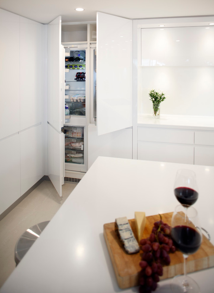 This is an example of a large contemporary l-shaped eat-in kitchen in Sydney with a drop-in sink, flat-panel cabinets, white cabinets, quartz benchtops, white splashback, stone slab splashback, stainless steel appliances and with island.