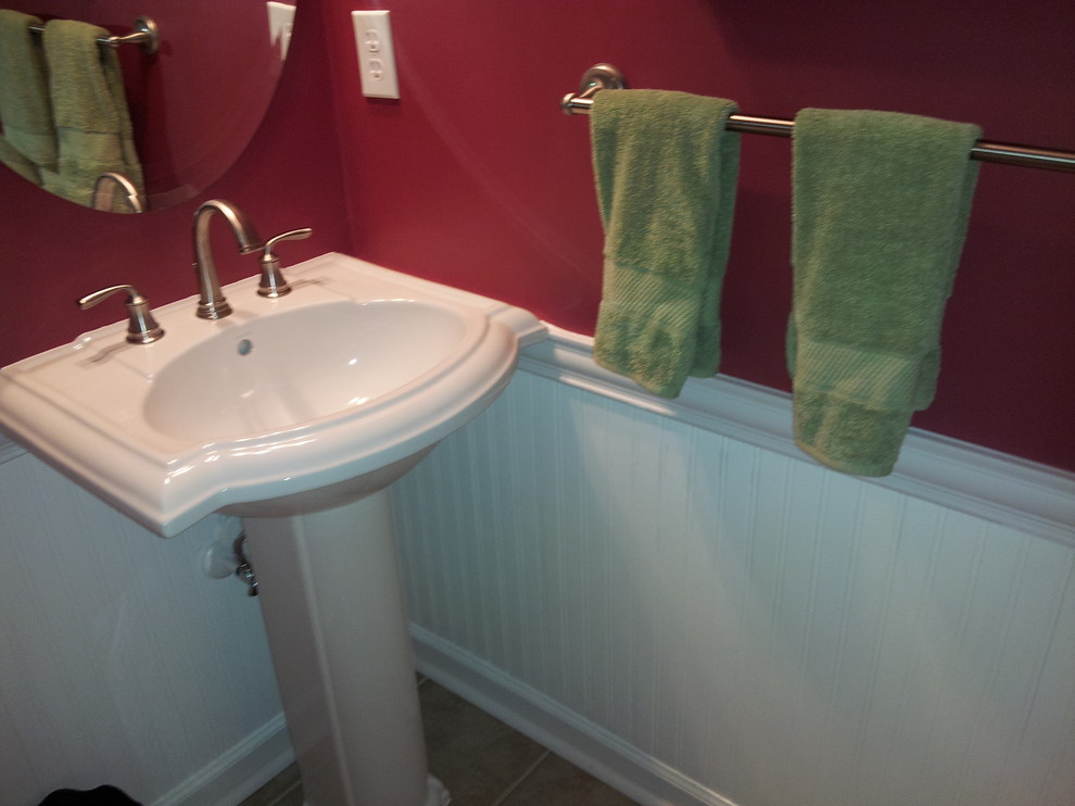 Photo of a small traditional powder room in Other with porcelain floors, red walls, a pedestal sink, a two-piece toilet and beige floor.