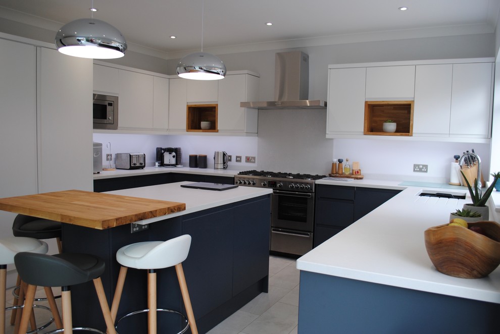 Inspiration for a mid-sized scandinavian u-shaped separate kitchen in Hertfordshire with a drop-in sink, flat-panel cabinets, stainless steel appliances, with island, grey floor and white benchtop.