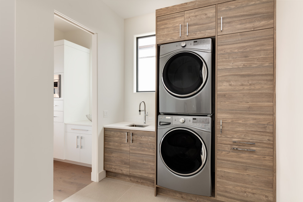 Immagine di una lavanderia multiuso moderna di medie dimensioni con lavello sottopiano, ante lisce, ante in legno scuro, top in quarzo composito, lavatrice e asciugatrice a colonna e top bianco